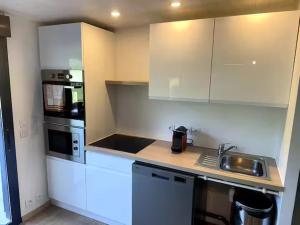 a kitchen with white cabinets and a counter top at Les lodges de Marie Chalet 3 in Banassac