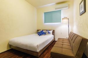 a bedroom with a bed and a couch and a window at 最大12名 広々庭付き ビーチ近く BBQ可 満天の星を楽しむ宿 やどかりハウス Yadokari House in Nakijin