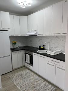 eine weiße Küche mit weißen Schränken und einer Spüle in der Unterkunft Green Heaven in Târgu Mureș