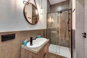 a bathroom with a sink and a shower and a mirror at Granaria Comfort Apartments in Gdańsk +191 photos