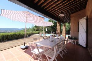 a table and chairs with umbrellas on a patio at La Villa Tara 4 chambres piscine privée vue panoramique sur les collines de Grimaud in Grimaud