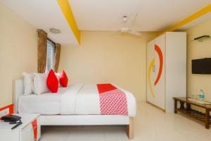 孟买Collection O Grand Corp Inn的卧室里有一张床，上面有红色和白色的枕头