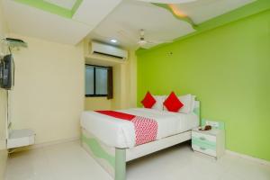 孟买Collection O Grand Corp Inn的一间卧室配有一张带绿色墙壁和红色枕头的床 更多16张照片