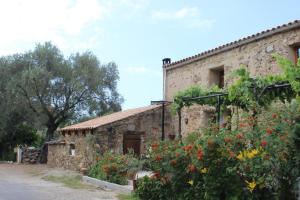 an old stone building with flowers in front of it at Auberge Pietra Monetta in Belgodère