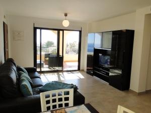 sala de estar con sofá negro y TV en Villa Marina CC2, en Águilas
