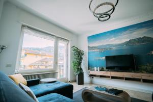 ein Wohnzimmer mit einer blauen Couch und einem großen Fenster in der Unterkunft Family Apartment Vista Lago in Stresa
