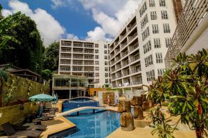 a hotel with a swimming pool in front of a building at Bay Shore Ocean View by Get A Rent Phuket in Patong Beach