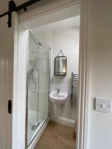 a white bathroom with a sink and a shower at The Parcel Shed Gilling East in Gilling East