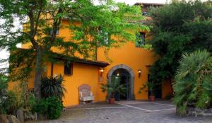 a yellow house with a bench in front of it at Hotel Antico Residence Roma in Monterosi