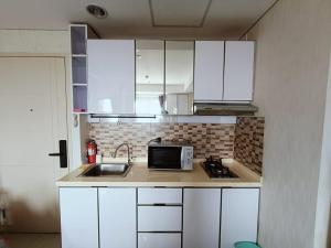 a kitchen with white cabinets and a sink and a microwave at Chiens168 in Cikarang