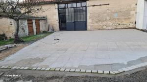 a concrete driveway with a dog on a hose in front of a building at Gite PMR Adapté Futuroscope Aquascope Center Parc Mecanick & Ko in Mirebeau