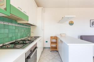 una cucina con armadi bianchi e piastrelle verdi di Salentoandmore - Terrazzo sul Mare a Torre Pali