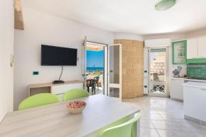 una cucina e una sala da pranzo con un tavolo e una televisione di Salentoandmore - Terrazzo sul Mare a Torre Pali