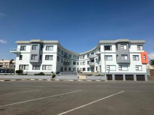 een groot wit gebouw met een parkeerplaats ervoor bij Ocean Wave No.1 Self Catering in Swakopmund