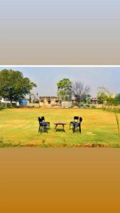 two chairs and a picnic table in a field at Ranthambore Bagh niwas in Khilchipur