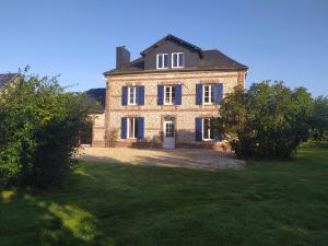 a large brick house with a large yard at Chambres d'Hôtes " Le Clos des Colimaçons " in Maniquerville