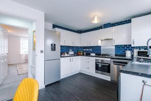 a kitchen with white cabinets and blue tiles at Vibrant Home in Crewe by 53 Degrees Property, Ideal for Business, FREE Parking! in Crewe