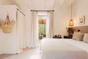 a white bedroom with a bed and a window at Finca Serena Mallorca, Small Luxury Hotels in Montuiri