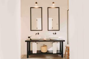 a bathroom with two sinks and two mirrors at Finca Serena Mallorca, Small Luxury Hotels in Montuiri