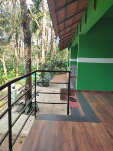Green Wayanad Homestay في Batheri: غرفة بجدار أخضر وأرضية خشبية +8 صور