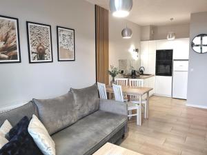 a living room with a couch and a kitchen with a table at Apartament BorMik, 150m od plaży, basen in Ustronie Morskie