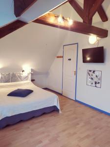 a bedroom with a large white bed in a attic at Chambres d'Hôtes " Le Clos des Colimaçons " in Maniquerville