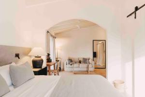 a bedroom with a white bed and a living room at Finca Serena Mallorca, Small Luxury Hotels in Montuiri
