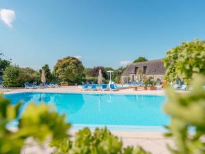 a large swimming pool with chairs and umbrellas at Camping de La Hallerais Dinan in Taden