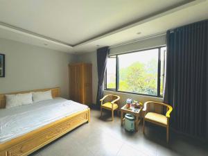 a bedroom with a bed and two chairs and a window at Kieu Anh Hotel Phu Tho in Thanh Sơn