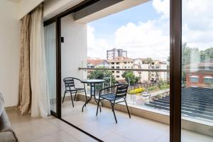 ナイロビにあるHarrys Nairobi Oasis at Astoria Apartmentsのバルコニー(テーブル、椅子付)、大きな窓が備わります。