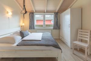 ダゲビュルにあるFerienhaus Herzmuschelのベッドルーム1室(ベッド1台、窓、椅子付)