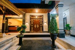 a front door of a house with two potted plants at Puri Kasih Home Stay in Sanur