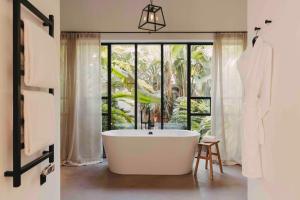 a bath tub in a bathroom with a large window at Finca Serena Mallorca, Small Luxury Hotels in Montuiri