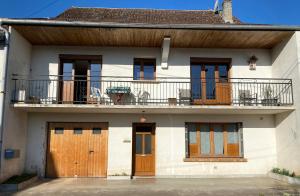 a white house with wooden doors and a balcony at Chez Doukine, Appartement avec balcon à Chouzelot in Chouzelot
