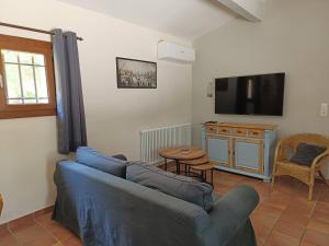 un soggiorno con un divano blu e una TV di Villa Provence élégante climatisée a Oppède