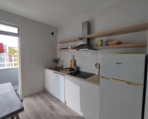 a kitchen with white cabinets and a white refrigerator at Oktheway Corme in Corme-Puerto