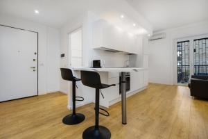 a white kitchen with a counter and two stools at Ray Home 2 SAN SIRO in Milan +22 photos