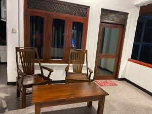 2 sillas y un banco en una habitación con ventanas en Wije House, en Dikwella