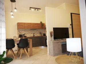 cocina con mesa, TV y sillas en Modern Two-Bedroom Flat, 10 Mins Walk To The Beach, en Quartu SantʼElena