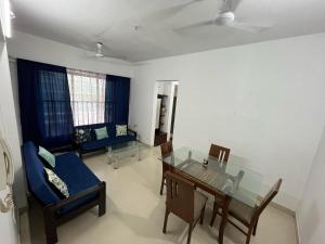 a living room with a glass table and a blue couch at Aarya Stays- 1BHK near Jupiter Hospital in Thane