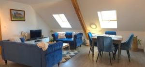 a living room with blue furniture and a table and chairs at Gîte des biches in Birkenwald