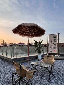 西安Xiyou Hotel Xi'an City Wall Branch禧又HOTEL的屋顶上配有一张桌子和两把椅子以及一把雨伞