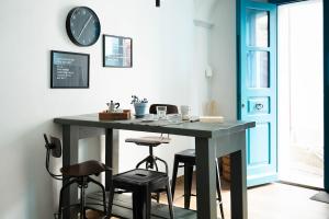a table in a room with stools and a clock on the wall at Appartamento Confortevole nel cuore del centro storico in Orosei +34 photos