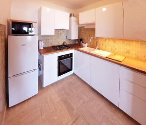 a kitchen with white cabinets and a white refrigerator at Bien-être & Panorama - Les Gîtes de la Côte d'Amour in Le Croisic