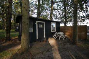 a black tiny house in the woods with a table at Bungalow WALD & SAND direkt am Strand in Dranske