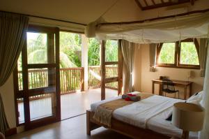 a bedroom with a bed and a balcony with windows at Owa Lodge Areguling in Kuta Lombok +37 photos