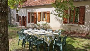 a table with wine glasses on it in front of a house at gite au jardin de grand-père in Fougères-sur-Bièvre