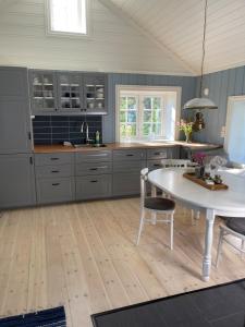 a kitchen with gray cabinets and a white table at Recently Refurbished Farm House in Larvik