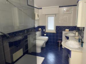 a blue tiled bathroom with two sinks and a toilet at Appartamento Maison Sabrina con vista giardino in Borgofranco dʼIvrea +23 photos