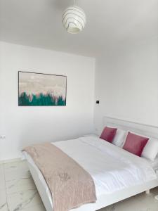 a white bedroom with a white bed with purple pillows at Villa Denis Ksamil in Ksamil